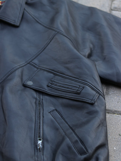 Close-up of black jacket panel stitching, snap detail and zip pocket